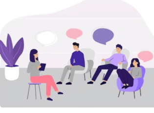 A group of people sitting in a circle in a classroom setting, with a facilitator leading a discussion at the front of the room.