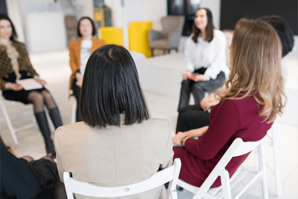 A group of women sharing their experiences in a peer-supported recovery program, emphasizing the importance of a shared connection in the recovery process