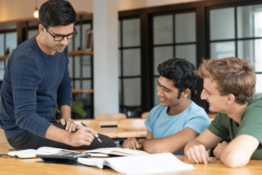 A group of young people studying together with a mentor, emphasizing the importance of youth mentoring programs in supporting their academic, social, and personal development