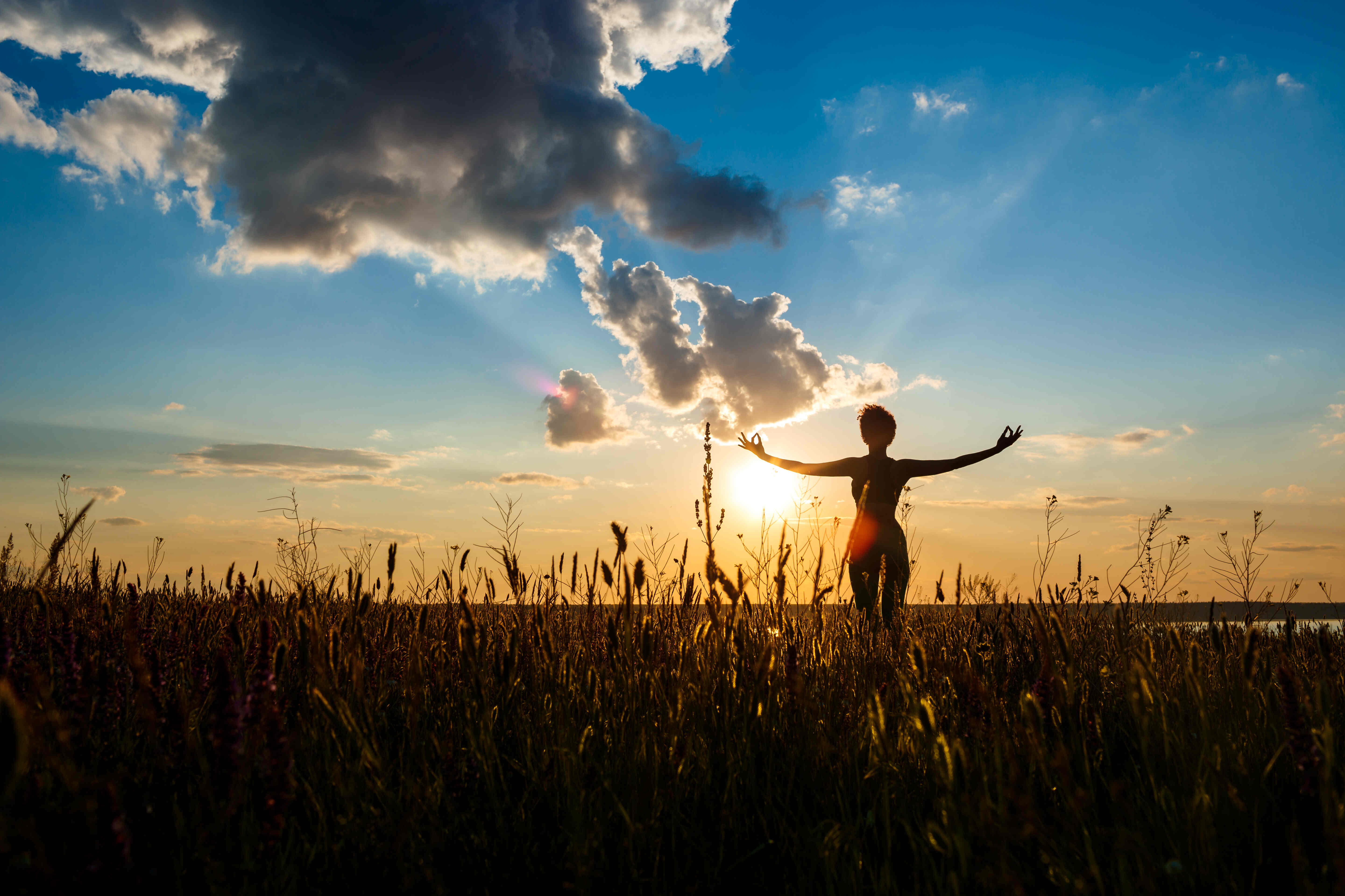 A woman in a yoga pose on a farm at sunrise, with the rolling hills and a barn in the background.